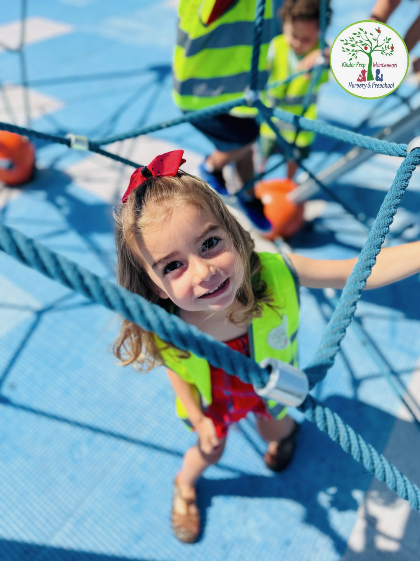 Happy girl climbing on rope playground equipment during summer camp activities
