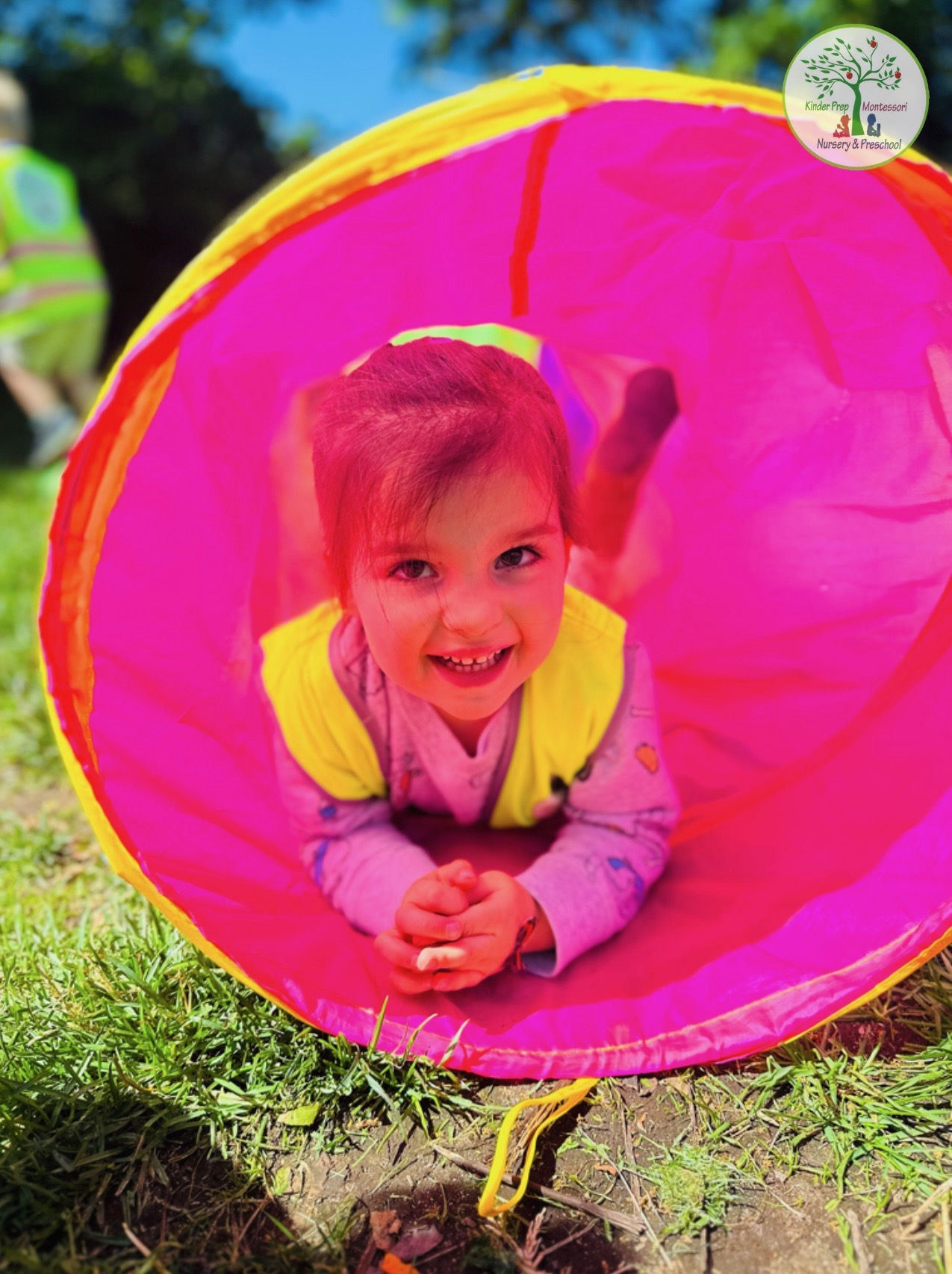Child playing in colorful tunnel during outdoor summer camp activities
